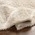 Tapis shaggy beige sur parquet en bois.