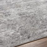 Tapis gris texturé sur plancher en bois.