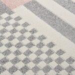 Tapis à motifs géométriques en gris et rose.