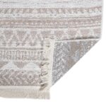 Tapis berbère beige à motifs géométriques et franges.