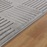 Tapis texturé gris sur parquet en bois.