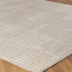 Tapis beige à motifs géométriques sur plancher en bois.