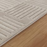 Tapis beige texturé sur parquet en bois.