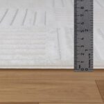 Règle mesurant une moquette blanche.