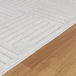 Tapis blanc texture géométrique sur parquet clair.