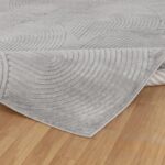 Tapis gris texturé sur plancher en bois.