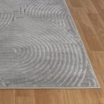 Tapis gris texturé en spirale sur parquet.