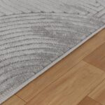 Tapis gris texturé sur plancher en bois.