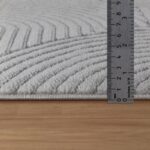 Règle mesurant épaisseur tapis sur parquet.