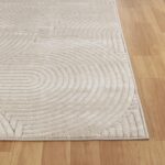 Tapis beige à motif concentrique sur plancher en bois.