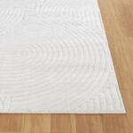 Tapis blanc à motif concentrique sur plancher en bois.