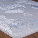 Tapis gris et bleu à motifs sur plancher en bois.