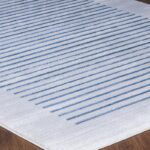 Tapis blanc à rayures bleues sur parquet.