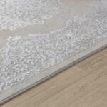 Tapis beige à motifs gris sur parquet clair.