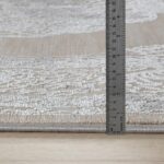 Règle mesurant épaisseur tapis sur plancher bois.