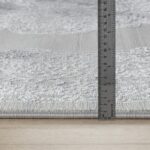 Mètre ruban mesurant un tapis gris.