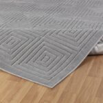 Tapis gris géométrique sur plancher en bois.
