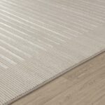 Tapis beige texturé sur plancher en bois.