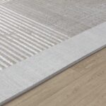 Tapis gris texturé sur plancher en bois.
