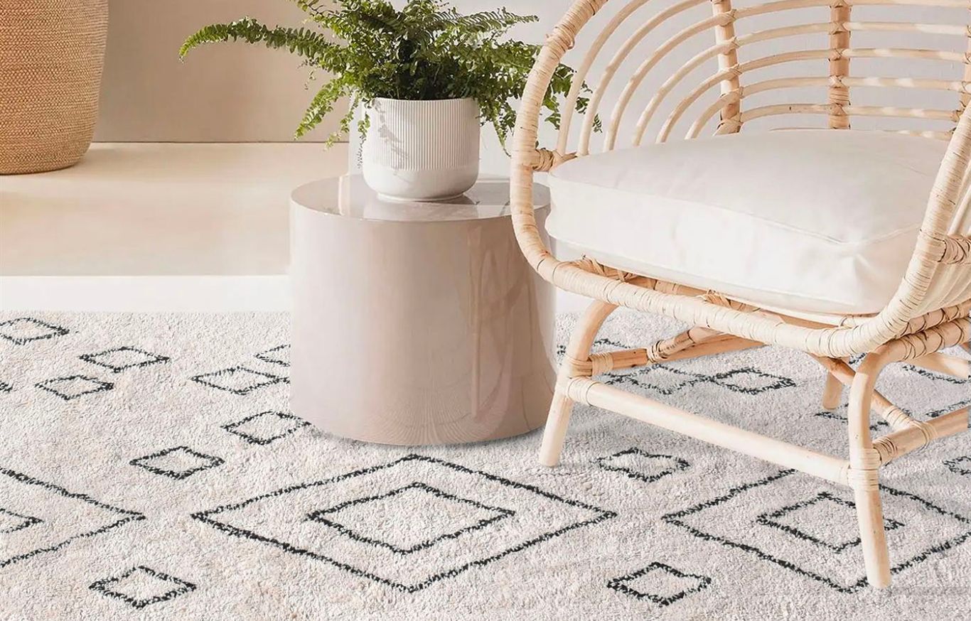 Salon chic avec fauteuil en rotin et tapis à motifs.