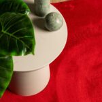 Table minimaliste, bougies, feuille verte, tapis rouge.