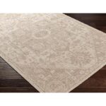 Tapis beige à motifs traditionnels sur plancher en bois.