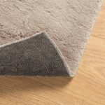 Tapis beige enroulé sur sol en bois.
