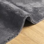Tapis gris doux sur plancher en bois.