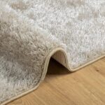 Tapis moelleux gris sur parquet en bois.