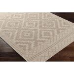 Tapis motif géométrique beige sur parquet brun.