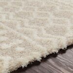 Tapis shaggy crème sur sol en bois.