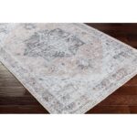 Tapis vintage gris et beige sur parquet.